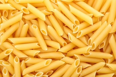 Photo of Uncooked penne pasta as background, closeup