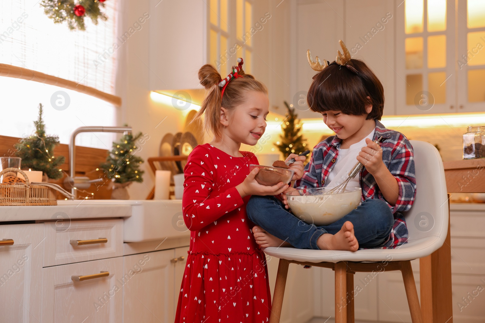 Photo of Cute little children making dough for Christmas cookies in kitchen