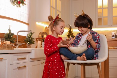 Photo of Cute little children making dough for Christmas cookies in kitchen