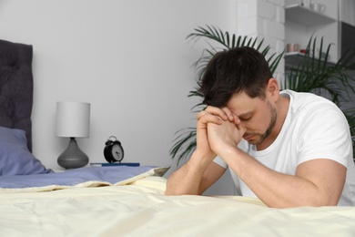 Photo of Handsome man saying bedtime prayer at home. Space for text