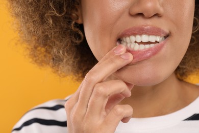 Woman showing her clean teeth on yellow background, closeup