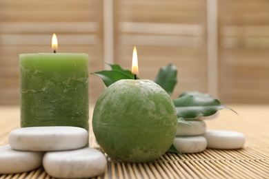 Photo of Composition with spa stones and candles on bamboo mat