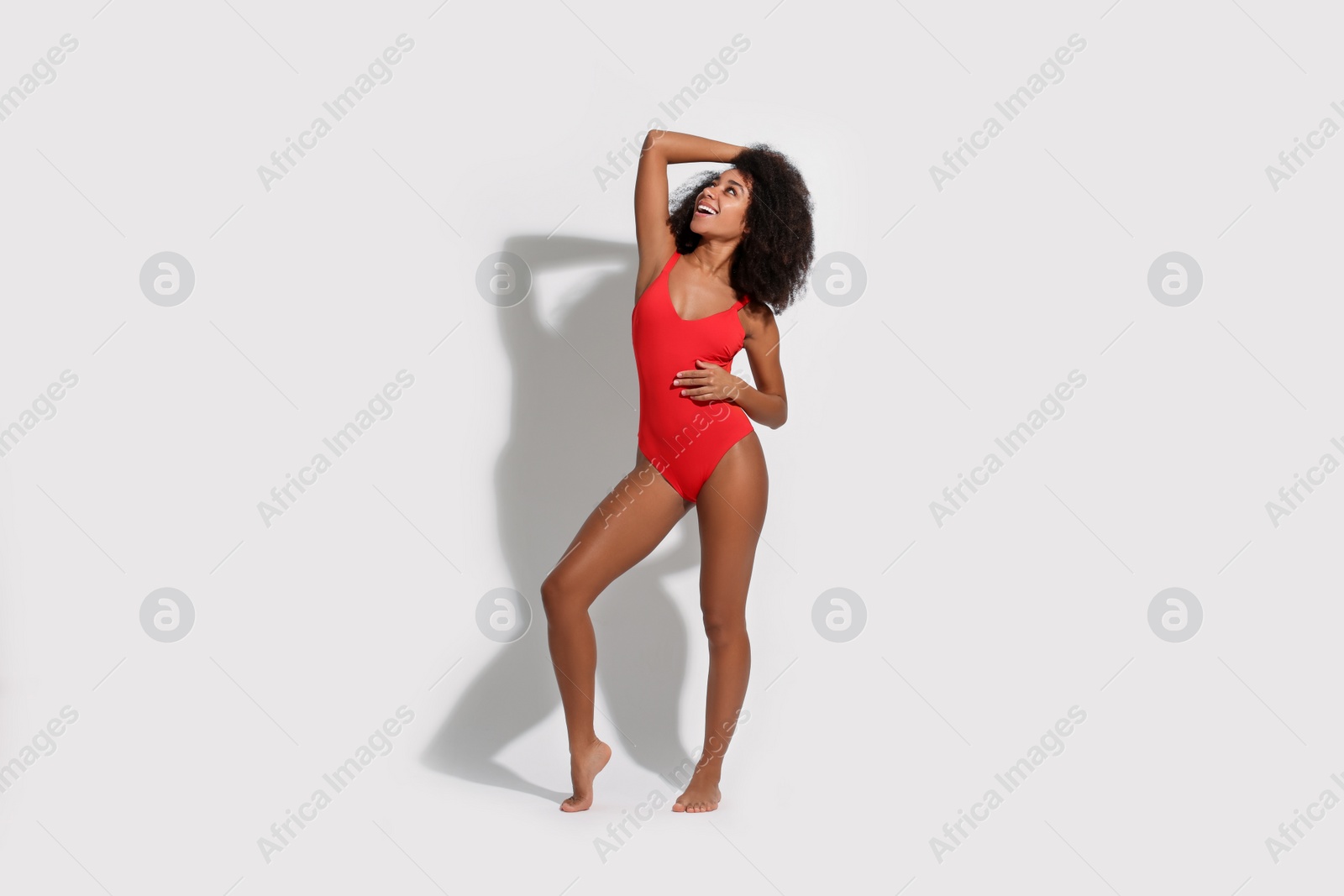 Photo of Beautiful woman in red one-piece summer swimsuit on white background