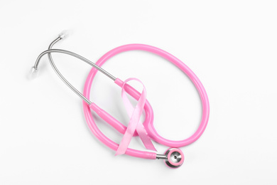 Photo of Pink ribbon and stethoscope on white background, top view. Breast cancer awareness