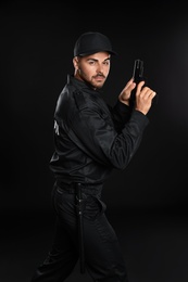 Male security guard in uniform with gun on dark background