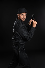 Photo of Male security guard in uniform with gun on dark background