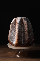 Delicious Pandoro cake decorated with powdered sugar on wooden table. Traditional Italian pastry