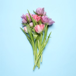 Photo of Beautiful colorful tulip flowers on light blue background, top view