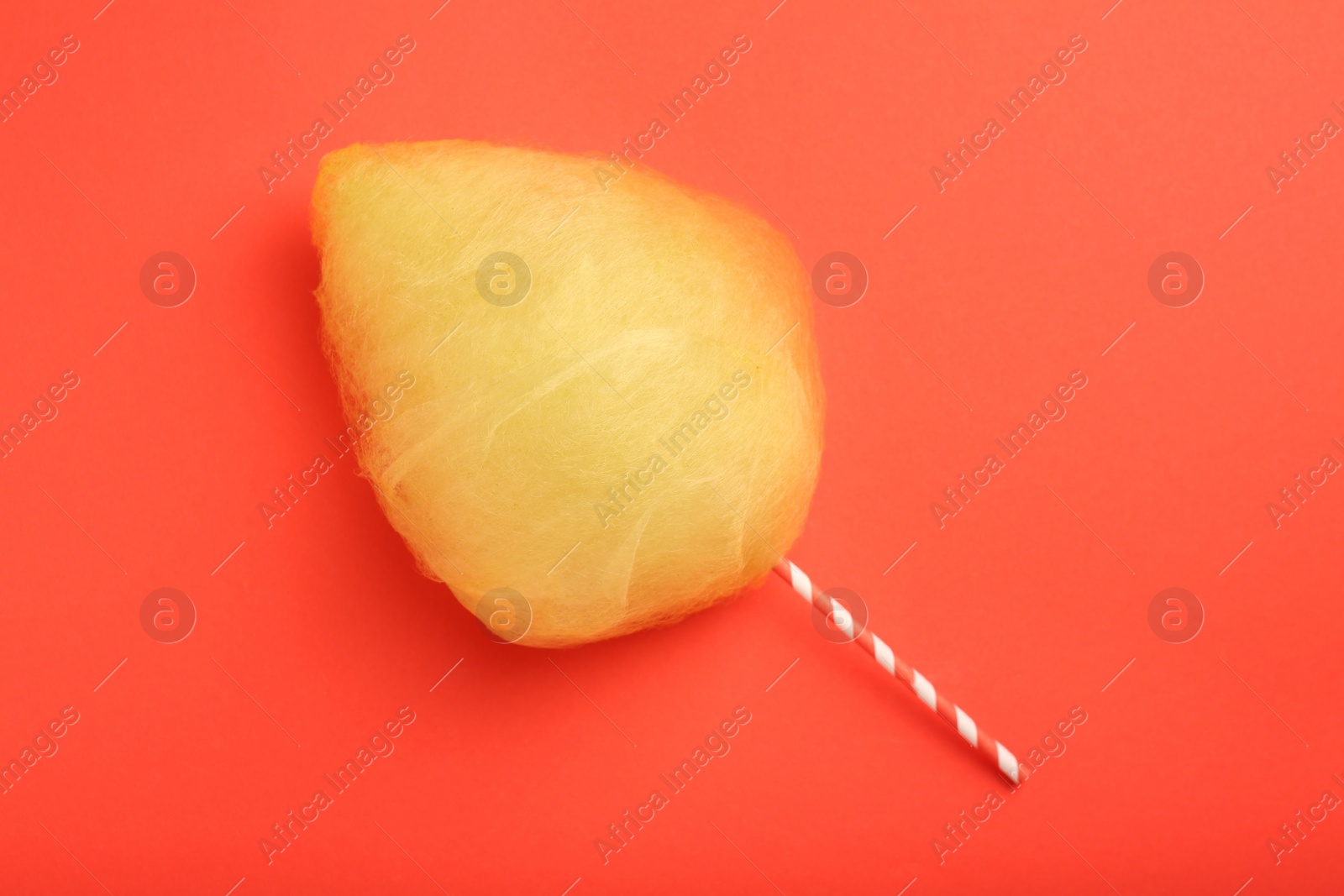 Photo of One sweet yellow cotton candy on red background, top view