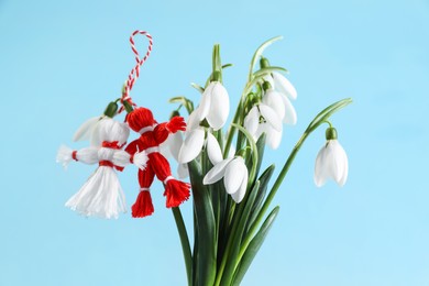 Photo of Traditional martisor and beautiful snowdrops on light blue background. Symbol of first spring day