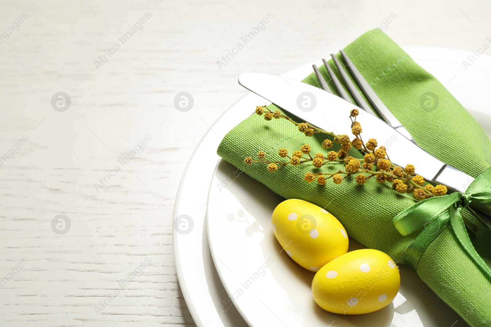 Photo of Festive Easter table setting with beautiful mimosa flowers and painted eggs, closeup. Space for text