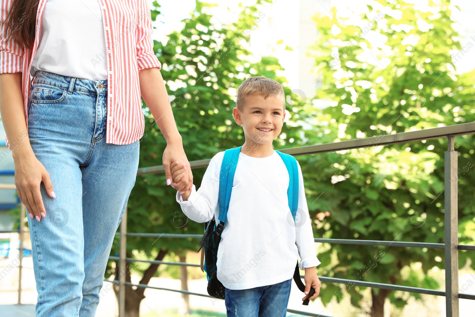 Photo of Young mother taking her little child to school outdoors