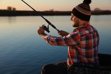 Photo of Fisherman with fishing rod at riverside. Recreational activity