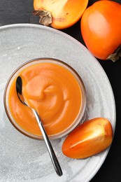 Photo of Delicious persimmon jam in glass bowl served on table, flat lay