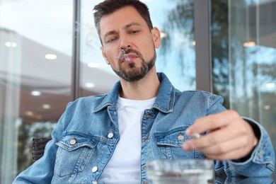 Photo of Handsome man smoking cigarette in outdoor cafe
