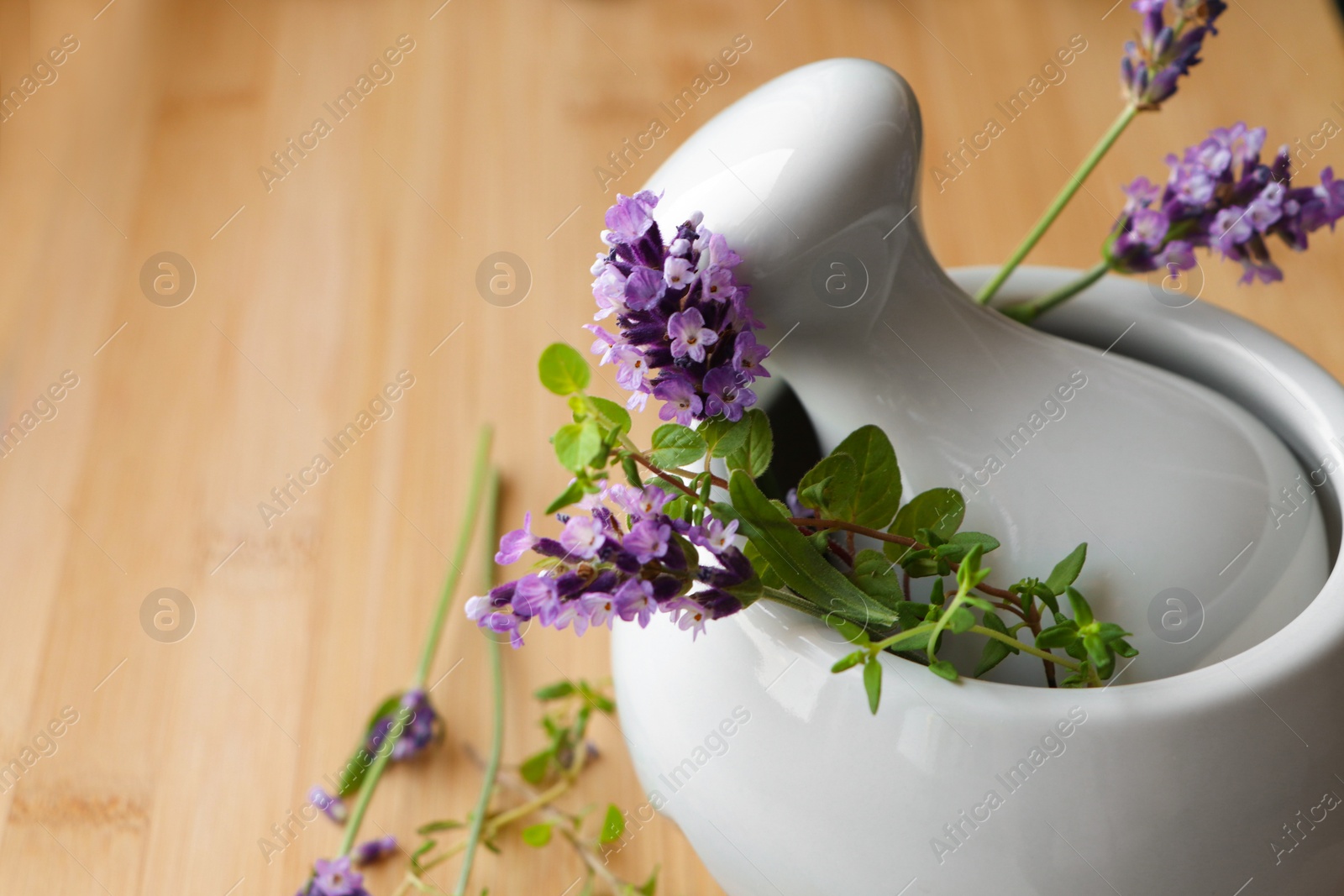 Photo of Mortar with fresh lavender flowers, green twigs and pestle on table, closeup. Space for text