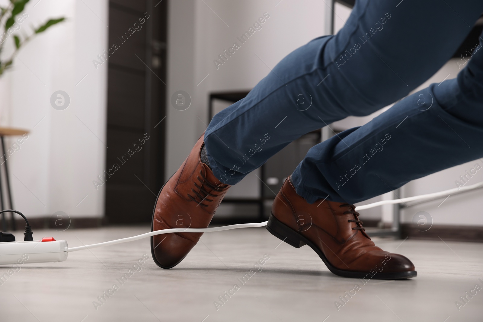 Photo of Man tripping over cord in office, closeup