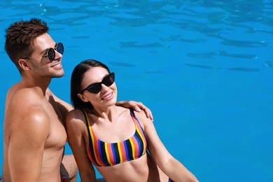 Photo of Woman in bikini with boyfriend near outdoor pool. Happy young couple