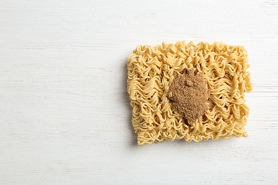 Photo of Block of quick cooking noodles with spices on wooden background, top view. Space for text