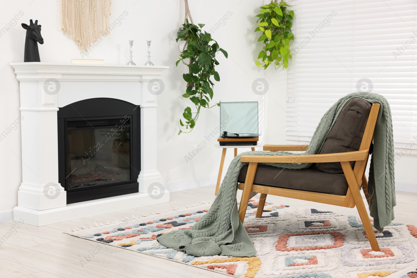 Photo of Stylish living room interior with comfortable armchair, blanket and fireplace