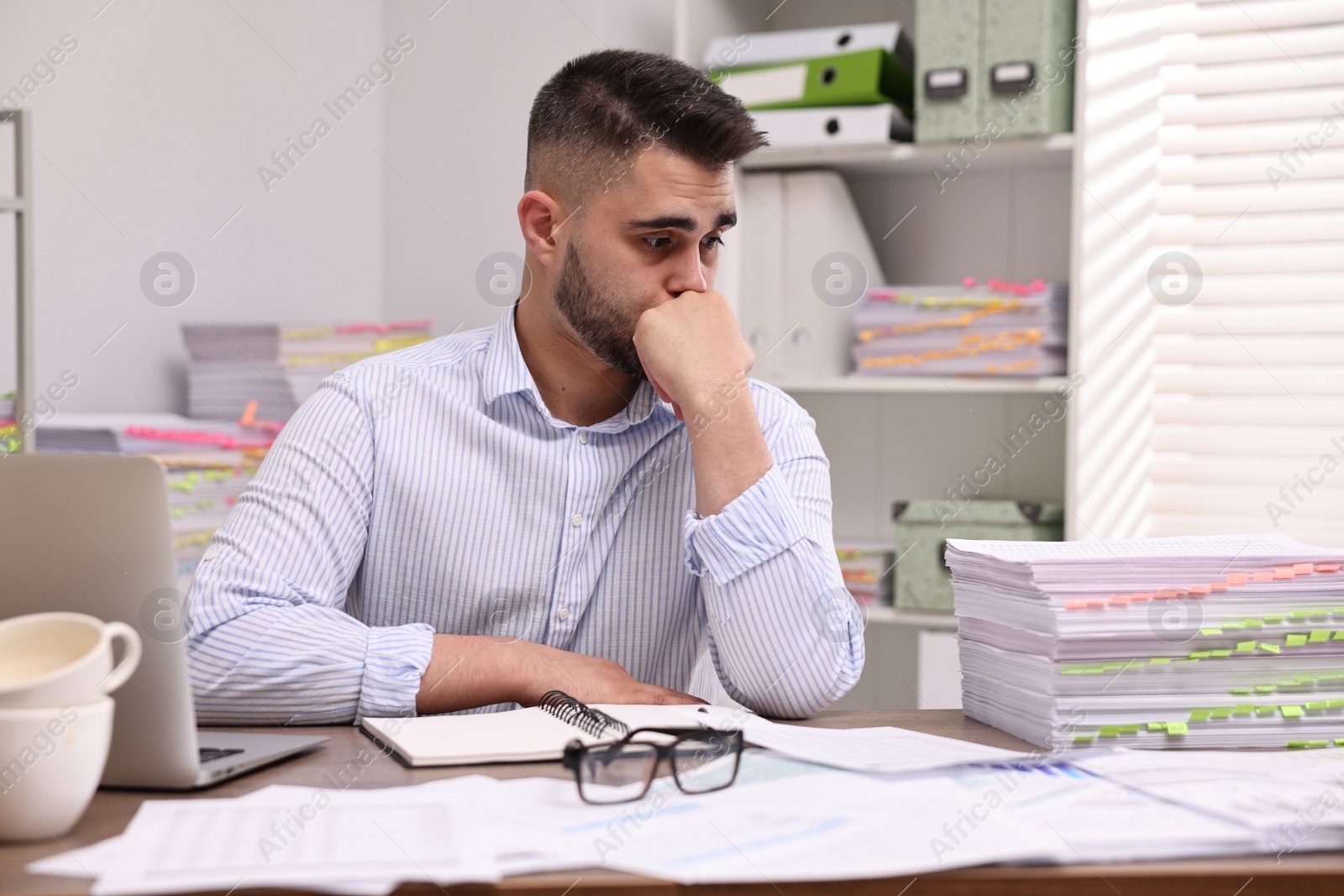 Photo of Overwhelmed man sitting at table in office