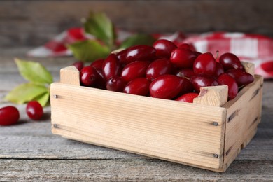 Photo of Fresh ripe dogwood berries in crate on wooden table, closeup