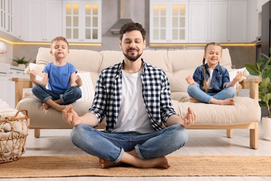 Photo of Father with children meditating together at home. Harmony and zen