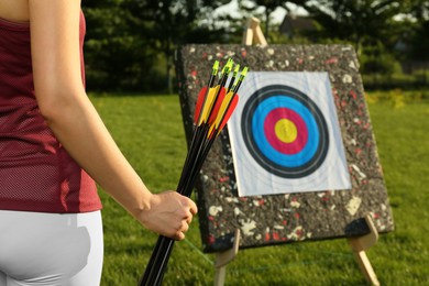 Photo of Woman with arrows near archery target in park, closeup