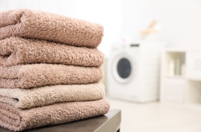 Stack of clean towels on table in bathroom.  Space for text