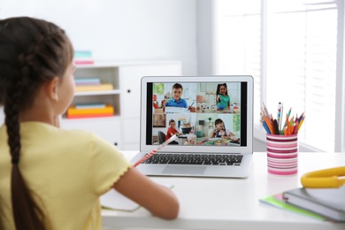 Distance learning during quarantine and lockdown due to Covid-19 pandemic. Girl having online school lesson with class indoors