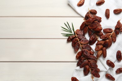 Photo of Tasty sweet dried dates and green leaf on white wooden table, flat lay. Space for text