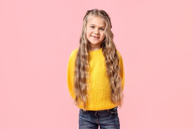 Photo of Cute little girl with braided hair on pink background