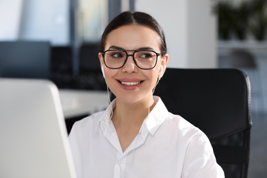 Photo of Happy woman with earphones using modern computer in office