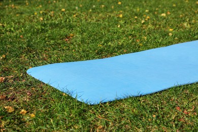 Photo of Blue karemat or fitness mat on fresh green grass outdoors