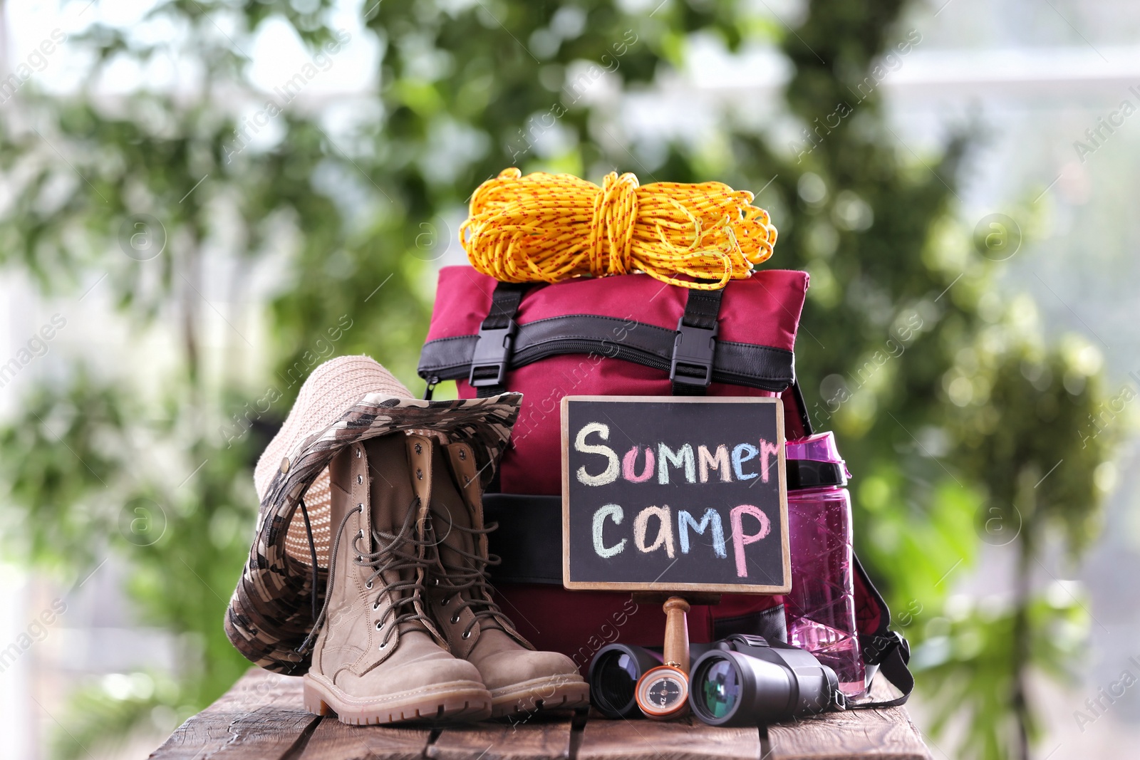 Photo of Composition with backpack and camping equipment on table against blurred background