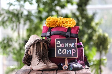Composition with backpack and camping equipment on table against blurred background