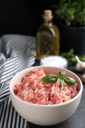 Raw chicken minced meat with basil on black table