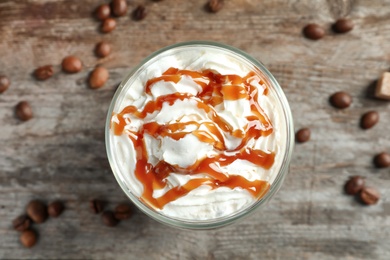 Photo of Glass of coffee with caramel topping on wooden background, top view