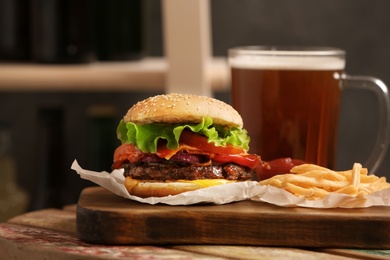 Photo of Burger, beer and french fries on table indoors