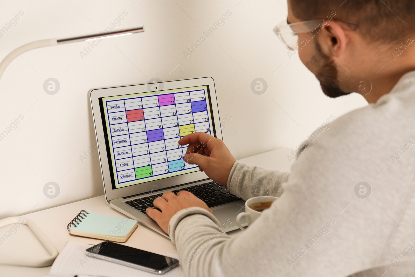 Photo of Young man using calendar app on laptop in office, closeup