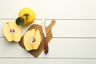 Tasty ripe quince fruits and knife on white wooden table, flat lay. Space for text