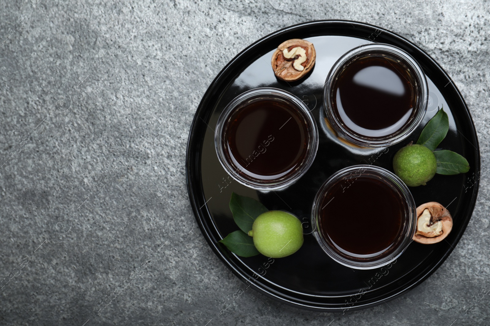 Photo of Delicious liqueur and fresh walnuts on grey table, top view. Space for text