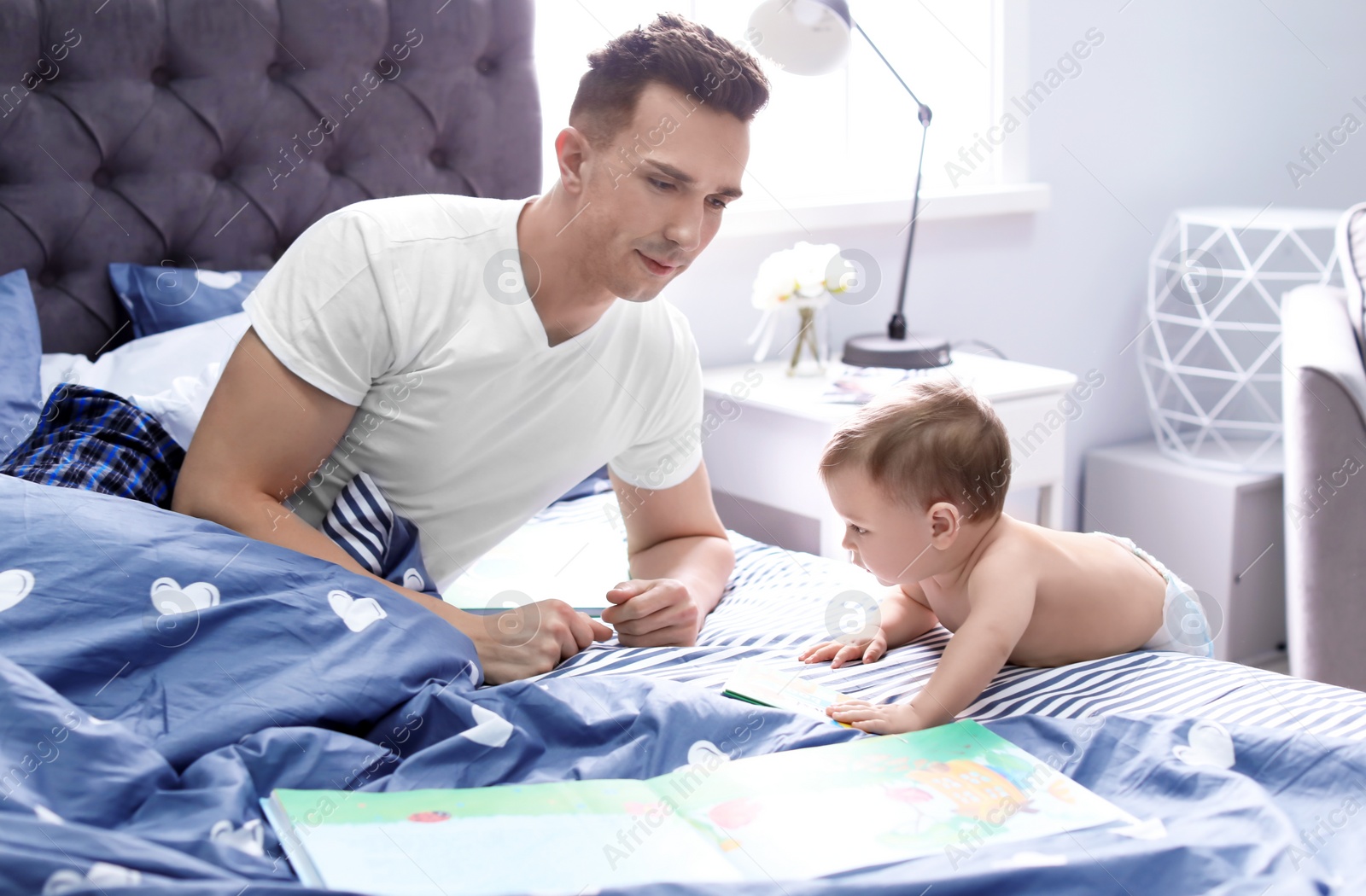 Photo of Young father with his cute little son on bed