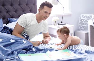 Young father with his cute little son on bed