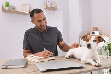 Young man with Jack Russell Terrier working at desk in home office