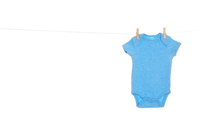 Photo of Baby onesie hanging on clothes line against white background. Laundry day