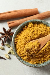 Photo of Dry curry powder in bowl and other condiments on light table, flat lay