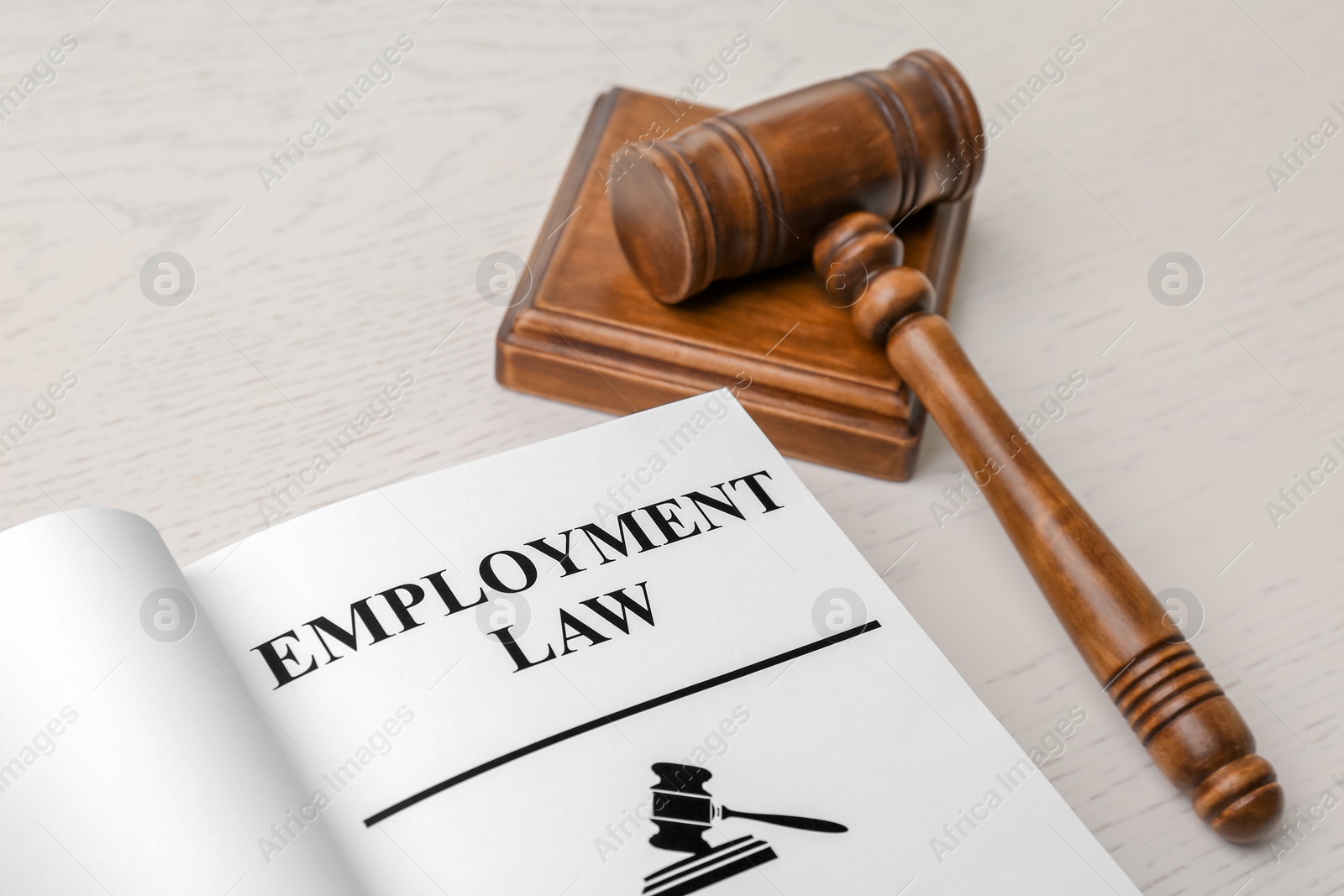 Photo of Open book with words EMPLOYMENT LAW and gavel on table, closeup