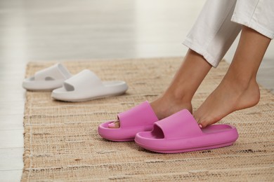 Photo of Woman putting on pink slippers indoors, closeup