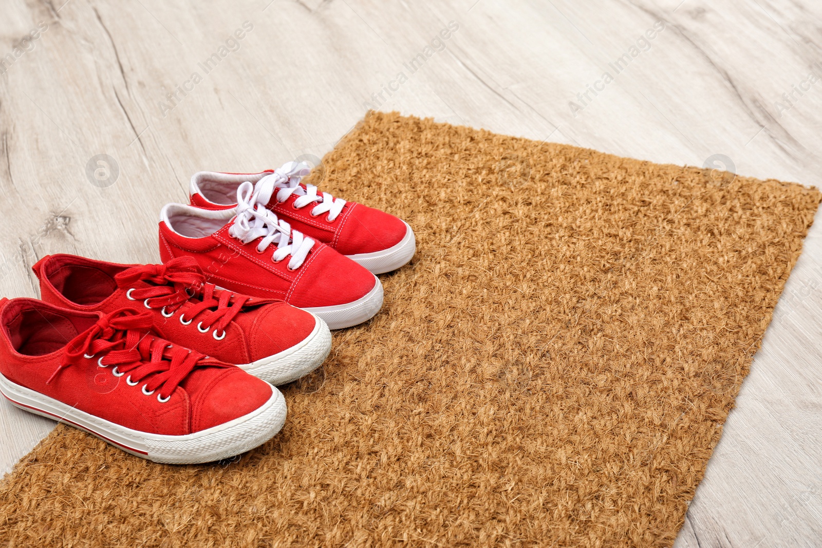 Photo of New clean doormat with shoes on floor. Space for text